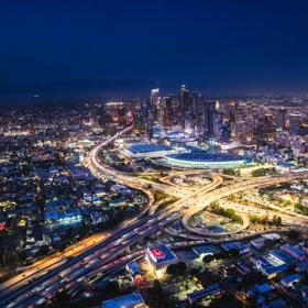 Aerial view of the Los Angeles skyline at night capturing the city lights across the area including downtown high rises and city highways.