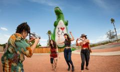 A band takes silly group photos in front of the Cabazon Dinosaurs. Shot as part of the 2024 Playful Journeys/Up Around The Bend brand campaign.