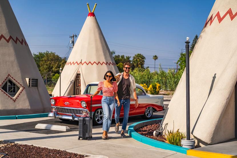Happy, smiling couple walking to their unique teepee motel room at the WigWam Motel located along the historic Route 66.